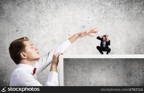 Aggressive boss. Angry businessman screaming at miniature of man colleague