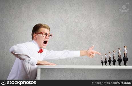 Aggressive boss. Angry businessman screaming at miniature of woman colleague