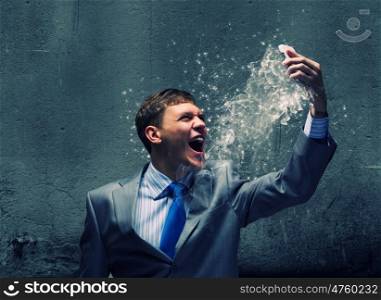 Aggressive business. Angry businessman screaming furiously in to mobile phone