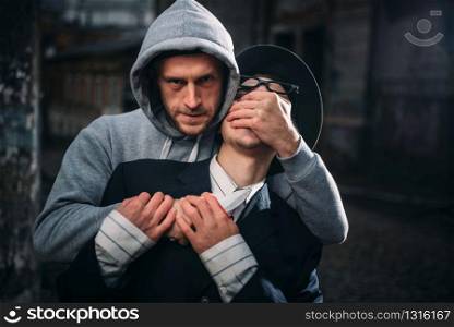 Aggressive thief with knife attack his victim on the night street. Gangster commits a robbery attack on a man. Crime concept. Thief with knife attack his victim on night street