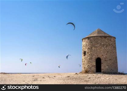 Agios Ioannis beach in Lefkas island Greece. Colorful power kites span across the sky from kite-surfers. Agios Ioannis is home to some old windmills.. Agios Ioannis beach in Lefkas island Greece