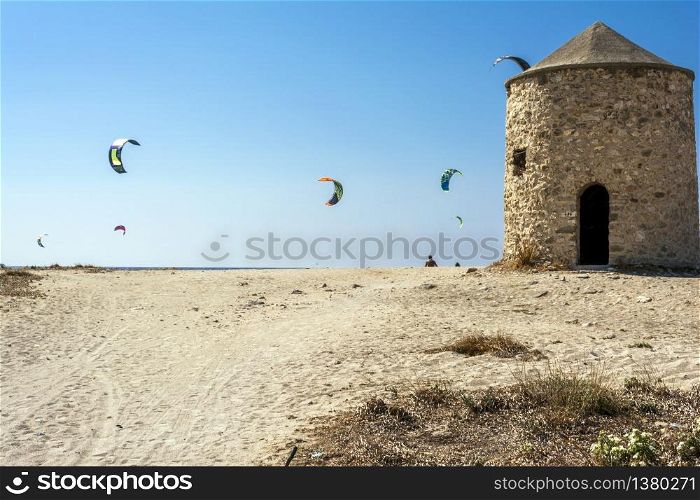 Agios Ioannis beach in Lefkas island Greece. Colorful power kites span across the sky from kite-surfers. Agios Ioannis is home to some old windmills.. Agios Ioannis beach in Lefkas island Greece