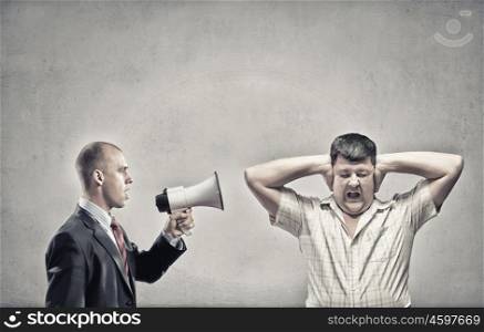 Agression in communication. Furious man screaming agressively in megaphone at man