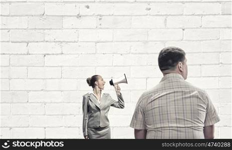 Agression in communication. Furious woman screaming agressively in megaphone at man