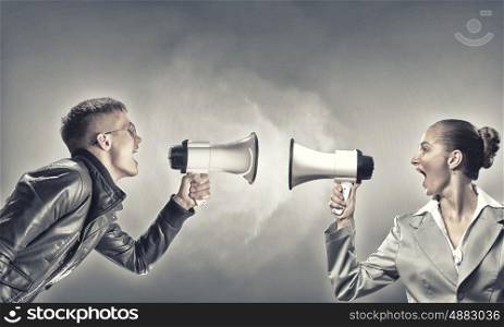 Agression in communication. Furious woman screaming agressively in megaphone at man