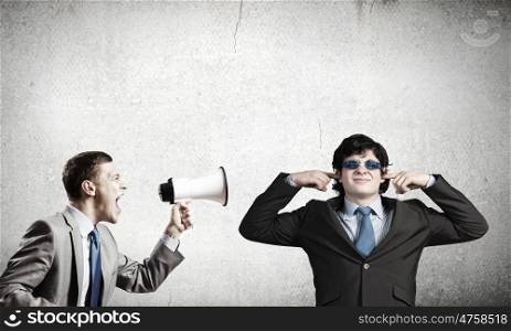 Agressive management. Young furious man screaming agressively in megaphone