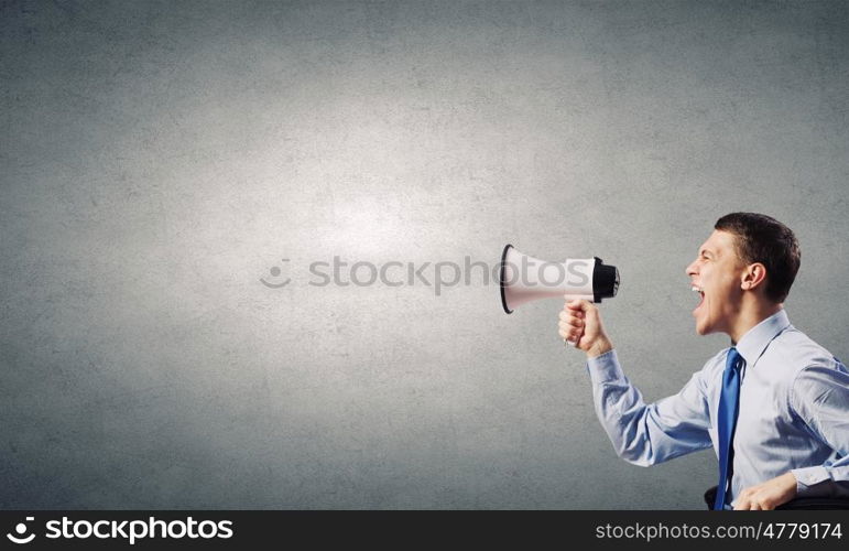 Agressive management. Young furious man screaming agressively in megaphone