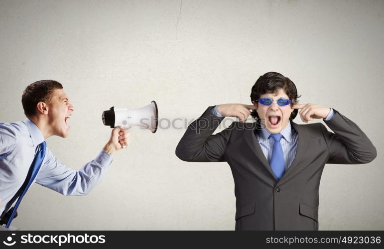 Agressive management. Young furious man screaming agressively in megaphone