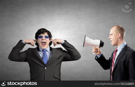 Agressive management. Young furious man screaming agressively in megaphone