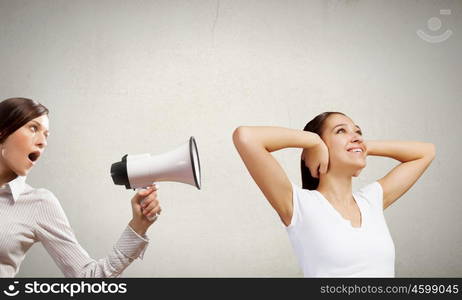 Agressive management. Young furious woman screaming agressively in megaphone