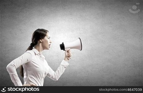 Agressive management. Young furious woman screaming agressively in megaphone