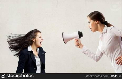 Agressive management. Young furious woman screaming agressively in megaphone