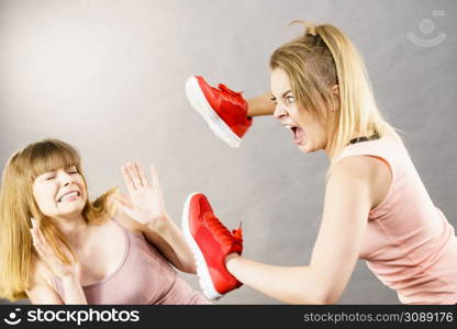 Agressive women having argue fight using shoes, female friend being scared. Violance concept.. Women fighting with shoes