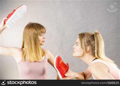 Agressive women having argue fight using shoes, female friend being scared. Violance concept.. Women fighting with shoes