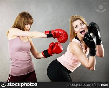 Agressive women having argue fight wearing boxing gloves, female friend being scared. Violance concept.. Agressive women fighting boxing with female