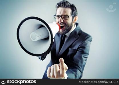 Agressive young businessman yelling over the megaphone