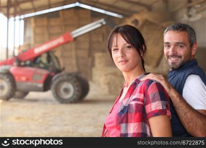 Agricultural couple in the barn with a tractor