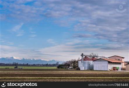 Agricultural landscape with farm, and in the background the Italian Alps