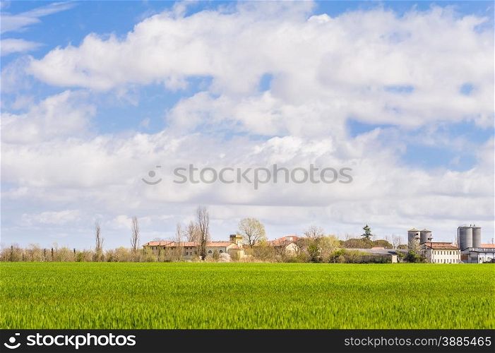 Agricultural landscape with farm and silos and a sky with clouds