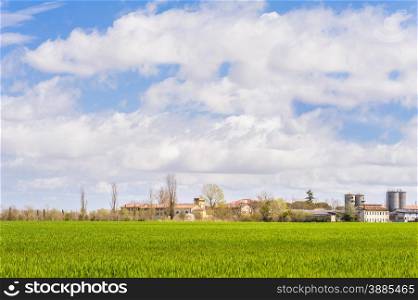 Agricultural landscape with farm and silos and a sky with clouds
