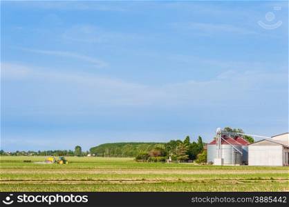 Agricultural landscape with farm,silos and tractor