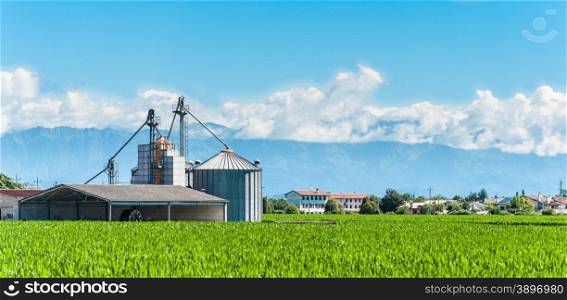 Agricultural landscape with old farm and silos and mountains in background
