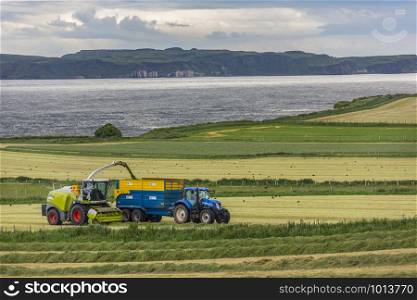 Agriculture - collecting silage in the fields near Ballycastle in County Antrim, Northern Ireland. Silage is grass fodder that is used as animal feed during the winter.