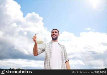 agriculture, farming, people and dairy concept - man or farmer with jug of milk at countryside