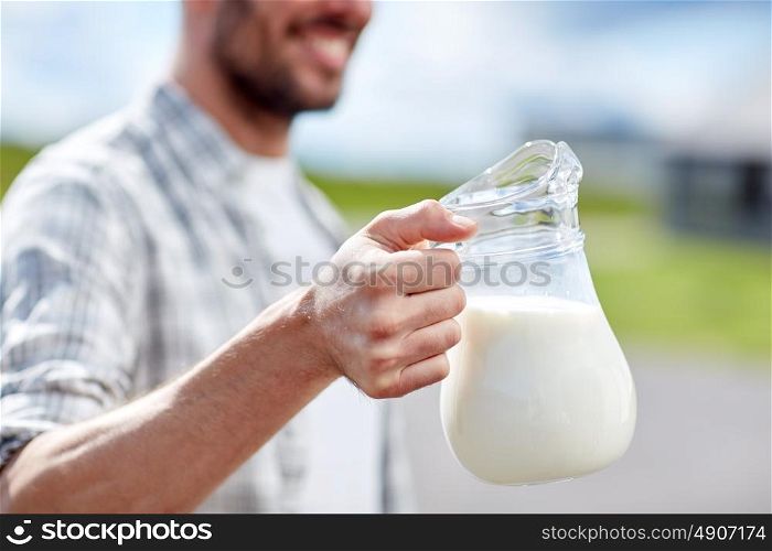 agriculture, farming, people and dairy concept - man or farmer with jug of milk at countryside. man or farmer with jug of milk at countryside