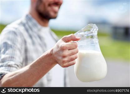 agriculture, farming, people and dairy concept - man or farmer with jug of milk at countryside. man or farmer with jug of milk at countryside