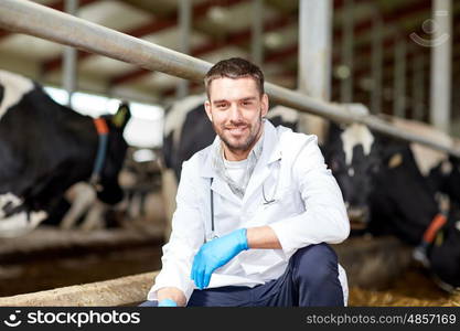 agriculture industry, farming, people and animal husbandry concept - veterinarian or doctor and cows in cowshed on dairy farm