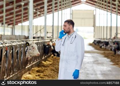 agriculture industry, farming, people and animal husbandry concept - veterinarian or doctor calling on smartphone with cows in cowshed on dairy farm