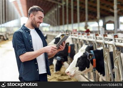 agriculture industry, farming, people, technology and animal husbandry concept - young man or farmer with tablet pc computer and cows in cowshed on dairy farm. young man with tablet pc and cows on dairy farm. young man with tablet pc and cows on dairy farm