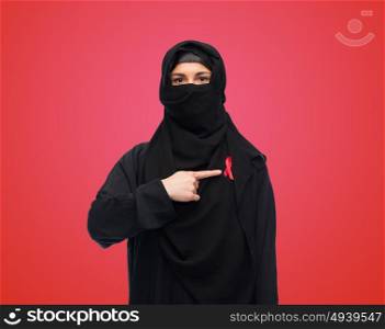 aids, hiv, healthcare and people concept - muslim woman wearing hijab and red awareness ribbon. muslim woman in hijab with red awareness ribbon