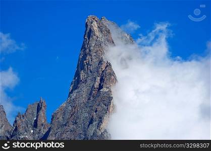 Aiguille Noire (Mont Blanc, Italy) rocky peak, while a growing cloud try to climb it.