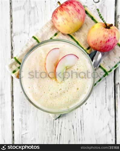 Air apple jelly in a glass bowl, a spoon and red apples on a towel on the background of the wooden planks on top