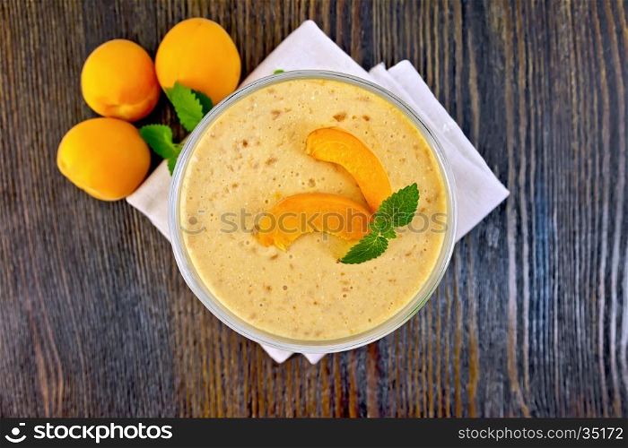 Air apricot jelly in a glass bowl, mint and fruit on a towel on the background of the wooden planks on top
