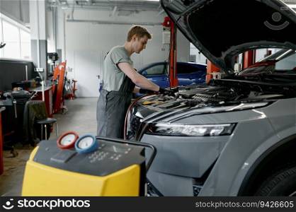 Air conditioner diagnostics and refilling machine at professional car service with male mechanic working with automobile. Air conditioner diagnostics and refilling machine