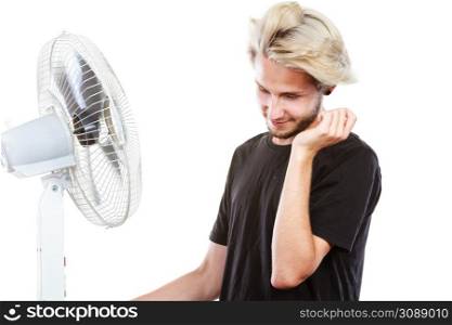 Air conditioning, heat, artistic concept. Young man in front of cooling fan, artistic way, studio shot isolated.. Young man in front of cooling fan
