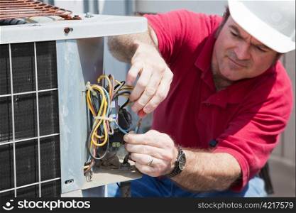 Air conditioning repairman rewiring a compressor unit. Focus on the man&rsquo;s hands and the wires.