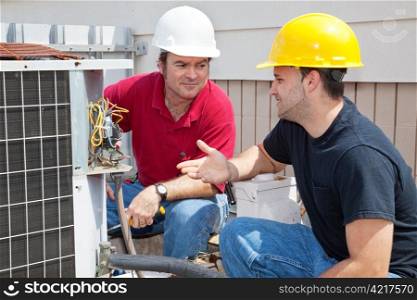 Air conditioning repairmen discussing the problem with a compressor unit.