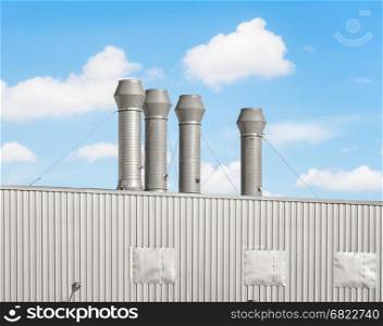 Air duct or steel pipe on roof of factory building with blue sky background.
