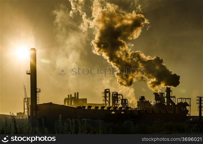 Air pollution coming from factory smoke stacks over sunset. Global concept earth preserving. Halt global warming