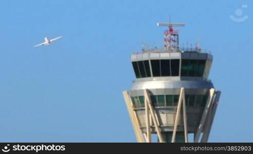 Air Traffic Control Tower at Barcelona Airport with flying plane in sky.Airport control tower at full capacity.Radar control tower with an airplane across the sky.