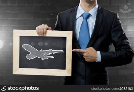 Air transportation. Close up of businessman holding chalkboard with airplane sketch