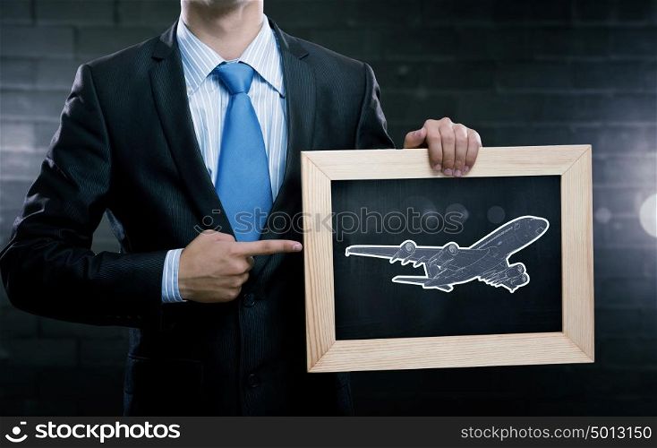 Air transportation. Close up of businessman holding chalkboard with airplane sketch