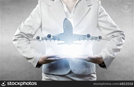 Air transportation. Close up of businesswoman hands holding airplane sign