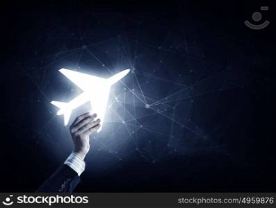 Air transportation concept. Close up of male hand holding airplane glowing sign