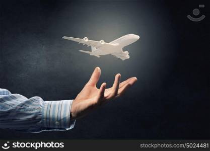 Air transportation concept. Close up of male hand holding airplane model