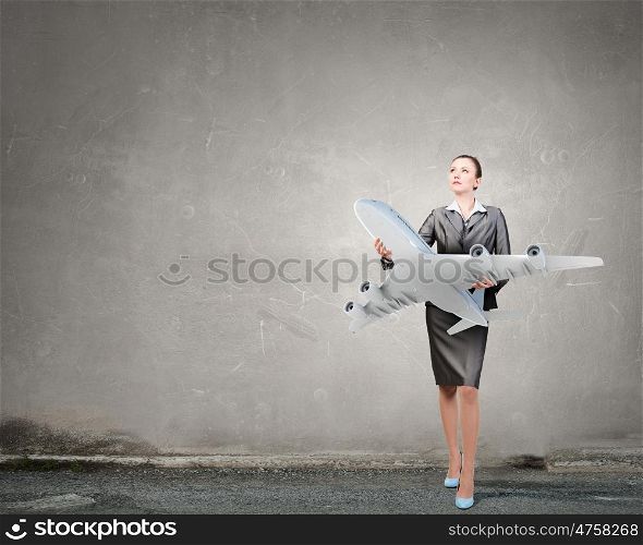 Aircraft or business travel concept. Attractive businesswoman holding airplane model in hands